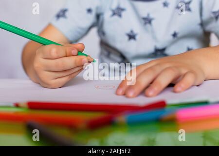 Close-up di childs mani disegno. Little Boy è in possesso di matite di colore. Il ragazzo, il disegno di una foto per i padri giorno. Piccolo Ragazzo attinge al tavolo. Foto Stock