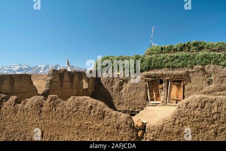 Tradizionale casa di villaggio , fango intonacato con foraggio animale sul tetto affiancato da Himalaya in estate in Komic, Himachal Pradesh, India. Foto Stock