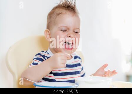 Il bambino mangia la minestra con le mani Foto Stock