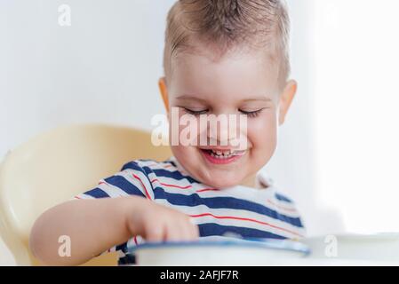 Il bambino mangia la minestra con le mani Foto Stock