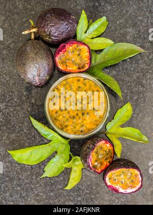 Laici composizione piana che mostra la passione frutta intera e a fette, Passione polpa di frutta e foglie Foto Stock