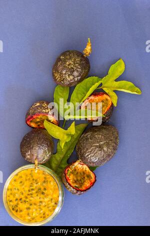 Posa piatto composizione con passione polpa di frutta, tutto il frutto della passione, fette di frutto della passione e le foglie dal vitigno di granadiglie Foto Stock