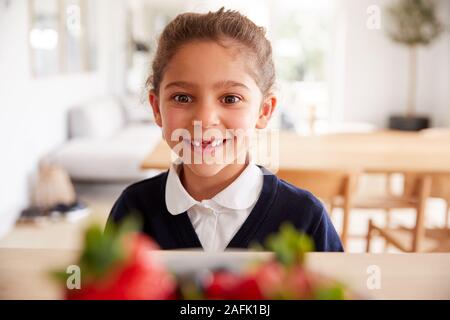 Maliziosa fanciulla che indossano uniformi scolastiche tenendo fragola dal bancone cucina Foto Stock