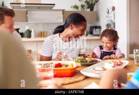 Multi-Generation razza mista famiglia pasto mangiando intorno al tavolo a casa insieme Foto Stock