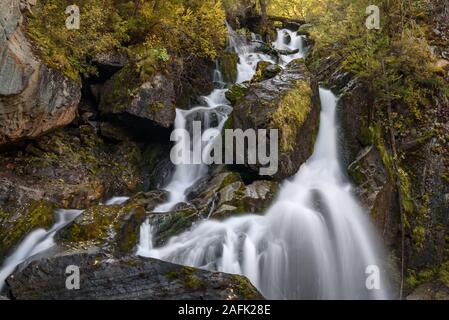 Bella cascata con acqua di seta su uno sfondo di rocce e sassi con muschio verde in montagna in autunno, girato a lunga esposizione Foto Stock