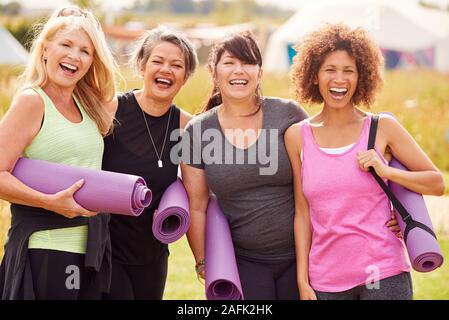 Ritratto di femmina matura amici su Outdoor ritiro di yoga camminando lungo il sentiero attraverso il campeggio Foto Stock