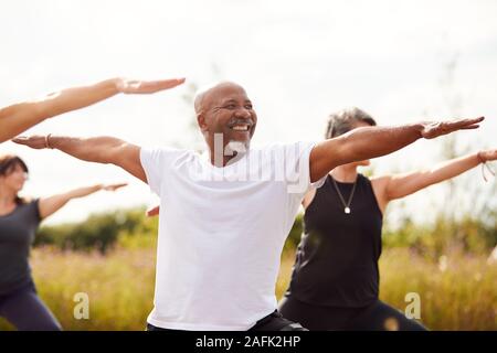 Un gruppo di uomini e donne adulti in classe a Outdoor ritiro di yoga Foto Stock