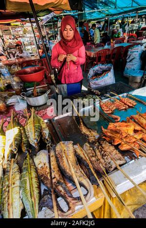 Donna con stallo del pesce alla brace & pollo su bastoni al mercato del granchio in questa città, famosa per i suoi piatti di pesce; Kep, Cambogia Foto Stock