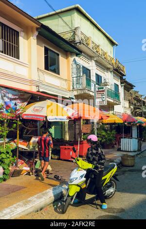 Ombrelloni e scooter a Dragon Street in questa colorata Vecchia coloniale francese porta sul fiume; Kampot, Kampot Provincia, Cambogia Foto Stock