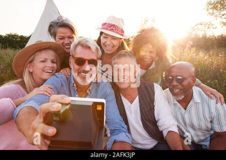 Gruppo di amici maturi in posa per Selfie al campeggio all'aperto Foto Stock
