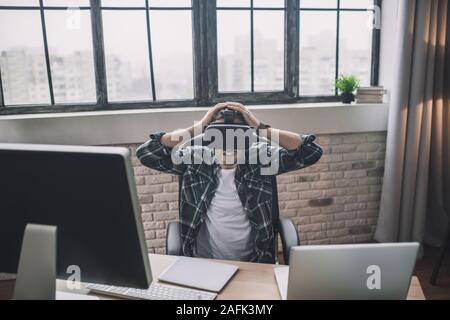 Uomo eccitato tramite auricolare VR in ufficio Foto Stock