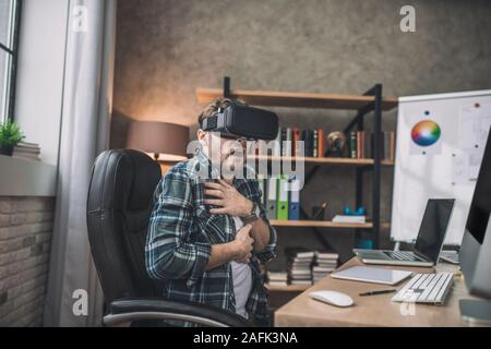 Sensazione di uomo spaventato mentre si utilizza la cuffia VR Foto Stock