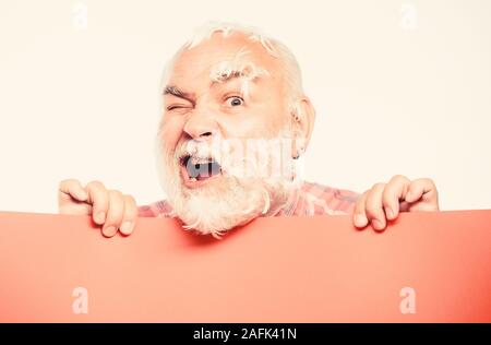 Spazio copia placare le informazioni. Hai bisogno di aiuto. barbiere. Senior uomo barbuto luogo annuncio su banner. scioccato uomo maturo con piume capelli grigi. Annuncio di ciò che sta accadendo. Foto Stock