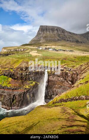 Cascata Gasadalur dal punto di vista durante una soleggiata giornata autunnale con l'acqua proveniente fino sotto un forte vento (Isole Faerøer, Danimarca, Europa) Foto Stock