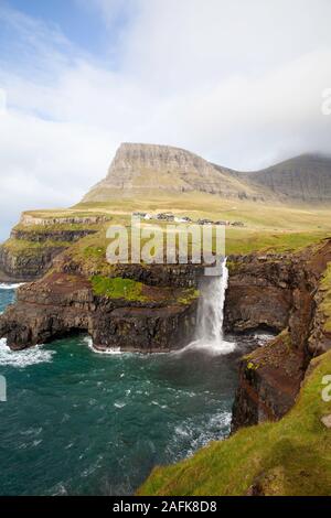 Cascata Gasadalur dal punto di vista durante una soleggiata giornata autunnale con l'acqua proveniente fino sotto un forte vento (Isole Faerøer, Danimarca, Europa) Foto Stock