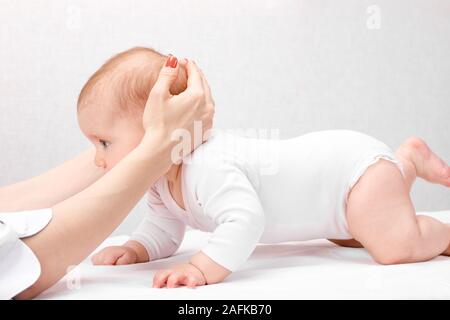 Sei mese bambina osteopatico di ricezione o il trattamento chiropratico in clinica pediatrica. Terapista manuale manipola chils della testa e del collo Foto Stock