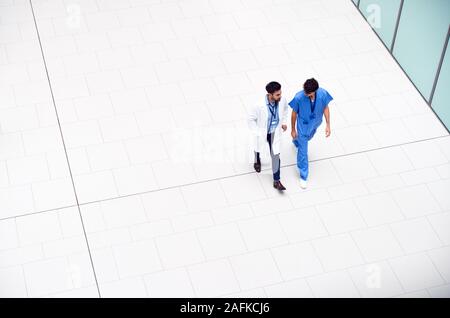 Vista aerea del personale medico a parlare come essi a piedi attraverso la Lobby del moderno edificio ospedaliero Foto Stock