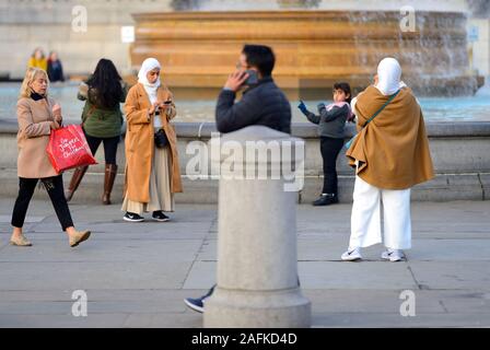 Londra, Inghilterra, Regno Unito. Donna musulmana a fotografare la figlia in Trafalgar Square Foto Stock