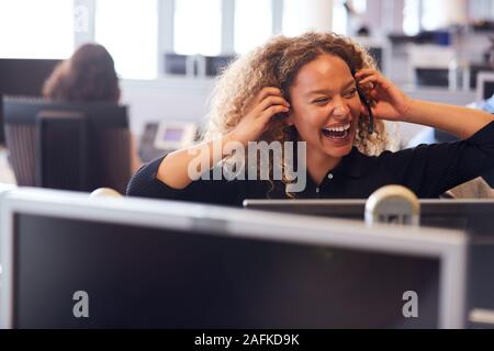 Ridendo imprenditrice indossando cuffia telefonica a parlare al chiamante nel Dipartimento di Servizio clienti Foto Stock