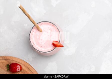 Bevanda indiana Strawberry Lassi in un bicchiere di vetro con carta paglia, Foto Stock