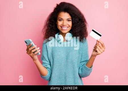 Close-up ritratto di lei bella attraente bella Allegro vivace-ondulato ragazza dai capelli tenendo nelle mani della banca di cellule card wireless Acquisto Acquisto di shopping Foto Stock