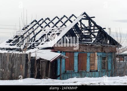 Rovine di un legno bruciato edificio residenziale in un paesaggio innevato Foto Stock