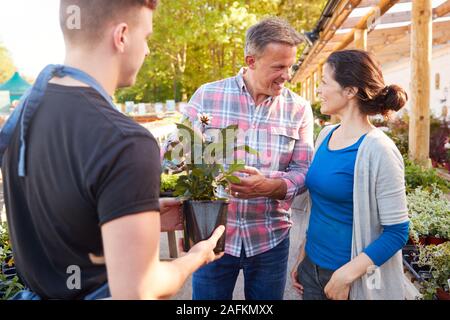 Coppia matura l'acquisto di piante da maschio assistente di vendita nel Centro giardino Foto Stock