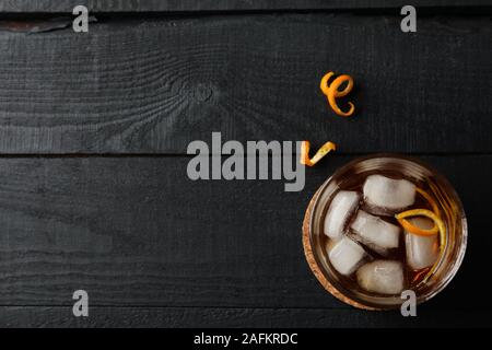 Bicchiere di whiskey e buccia d'arancia su sfondo di legno, vista dall'alto Foto Stock