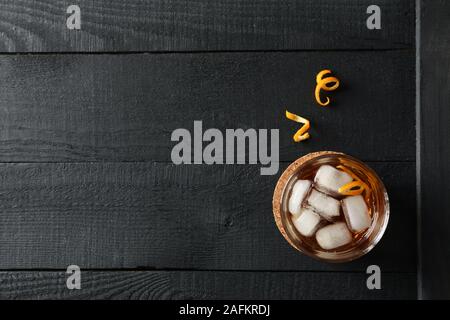 Bicchiere di whiskey e buccia d'arancia su sfondo di legno, vista dall'alto Foto Stock