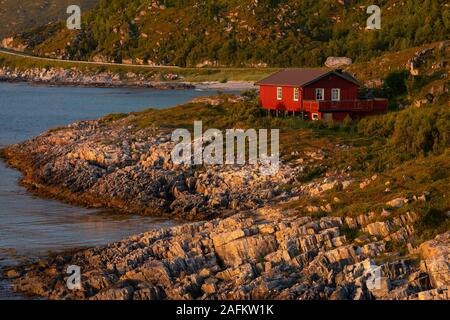 SOMMARØYA, Norvegia - Casa Rossa sulla costa rocciosa, il sole di mezzanotte, Troms, Norvegia settentrionale. Foto Stock