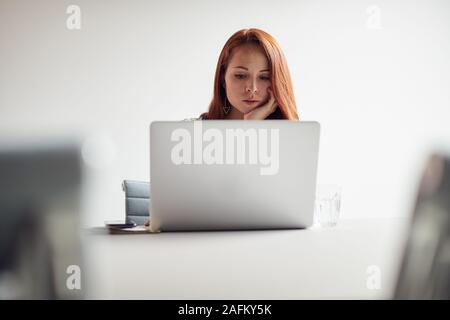 Casualmente vestito giovane imprenditrice lavorando sul computer portatile alla reception in moderni posti di lavoro Foto Stock