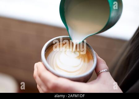 Chiusura del barista rendendo Design nella tazza di caffè presso il Cafe Foto Stock