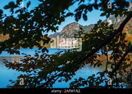 Vista sulla Alpsee in Baviera, circondato da naturale colori autunnali, vicino alla città di Füssen verso un complesso di case nel tipico stile architettonico. Foto Stock