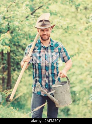 La piantumazione di alberi di tradizione. La coltivazione di piante. Coppia guy cappello da cowboy con annaffiatoio e pala. Arbor Day. La piantagione di alberi. Impegno e responsabilità. Concetto di agricoltura. La semina in giardino. Foto Stock