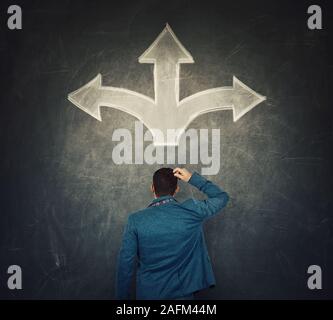 Vista posteriore di imprenditore perplesso di fronte a una lavagna, pensando circa la sua prossima mossa come crocevia frecce schizzo mostra tre possibili modi per scegliere Foto Stock