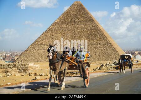 I turisti in un horsecart davanti alle piramidi a Giza, il Cairo, Egitto Foto Stock