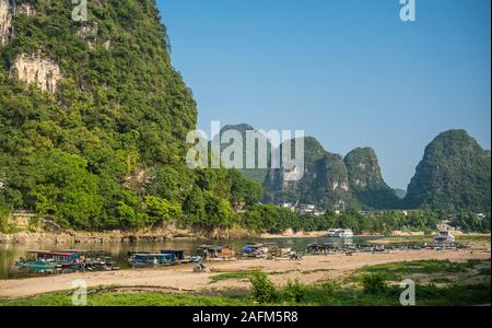 Yangshuo, Cina - Agosto 2019 : vista panoramica del fiume OLi shore con piccolo turista e barche di pescatori sulla riva del fiume, la traversata in traghetto e puntare Foto Stock