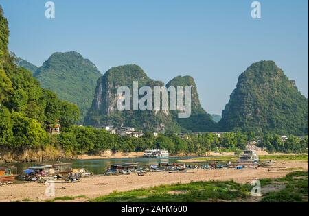 Yangshuo, Cina - Agosto 2019 : vista panoramica del fiume OLi shore con piccolo turista e barche di pescatori sulla riva del fiume, la traversata in traghetto e puntare Foto Stock