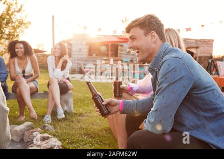 Un gruppo di giovani amici presso il Festival di musica seduto fuori e bere birra Foto Stock