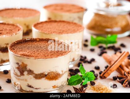 Tiramisù classico dessert in un vetro cosparso di cacao e decorate con i chicchi di caffè su un sfondo di legno, dessert di lusso Foto Stock