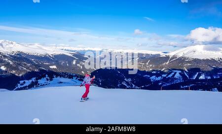 Uno snowboarder andando giù il pendio in Turrach, Austria. Piste perfettamente preparate. Le alte montagne che circondano la donna che indossa pantaloni rosa e colore Foto Stock