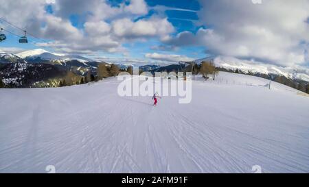 Uno snowboarder andando giù il pendio in Turrach, Austria. Piste perfettamente preparate. Le alte montagne che circondano la donna che indossa pantaloni rosa e colore Foto Stock