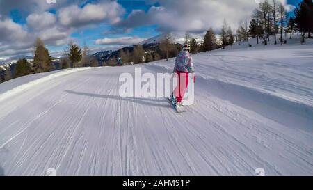 Uno snowboarder andando giù il pendio in Turrach, Austria. Piste perfettamente preparate. Le alte montagne che circondano la donna che indossa pantaloni rosa e colore Foto Stock