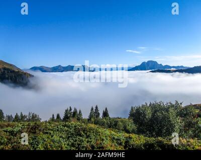 Una vista panoramica sulla vallata alpina. La valle è avvolta nella nebbia fitta, solo alti picchi di montagna sono visibili. Sentieri per escursioni in alta montagna. Endl Foto Stock