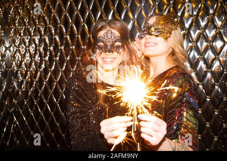 Due belle ragazze allegro in maschere veneziane godendo di partito nel night club Foto Stock