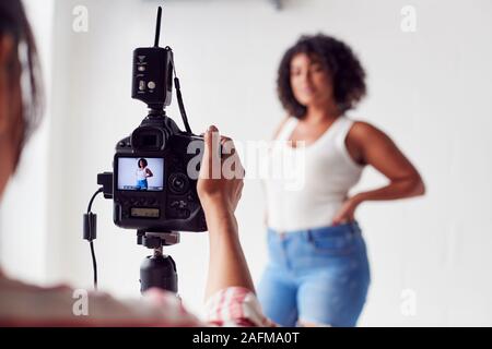 Fotografo femmina in Digital Studio le riprese di immagini sulla fotocamera collegato al computer portatile Foto Stock