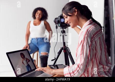 Fotografo femmina in Digital Studio le riprese di immagini sulla fotocamera collegato al computer portatile Foto Stock