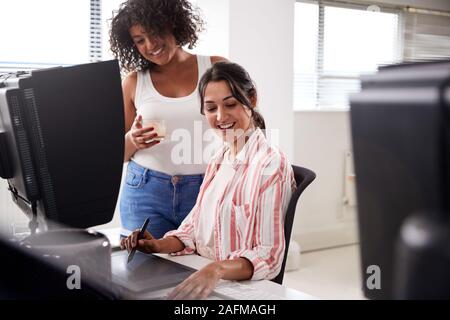 Due femmina Retouchers lavora al computer utilizzando tavoletta grafica in società di post-produzione Foto Stock