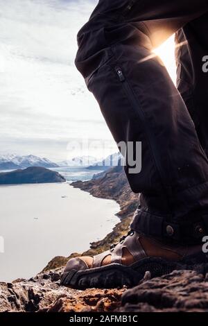 Ritagliare le gambe dei maschi di viaggiatori in scarpe da trekking su roccia Foto Stock