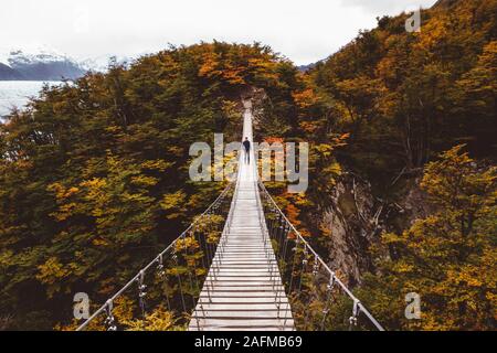 Uomo in piedi sul ponte di sospensione in montagna Foto Stock